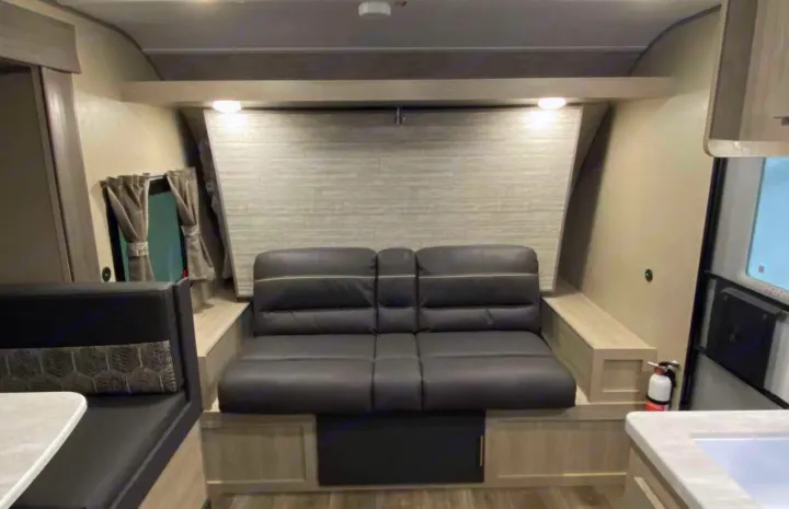Discover this RV rental interior with a dark sleeper sofa, dining booth, and efficient, light-toned living space.. Forest River Coachmen Catalina Summit 2022