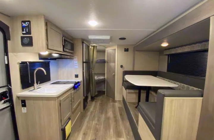 This modern RV rental interior features a well-equipped kitchen, comfortable dinette, and visible bunk beds for travel comfort.. Forest River Coachmen Catalina Summit 2022