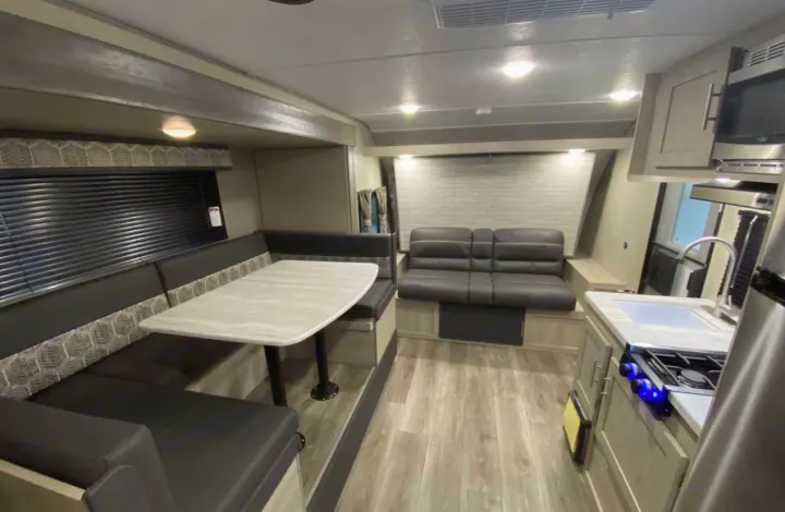 Inside this cozy RV rental: features a comfortable dinette, lounge seating, and a compact kitchen setup.. Forest River Coachmen Catalina Summit 2022