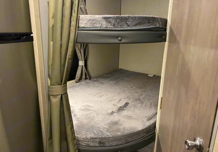 Cozy bunk beds in an RV rental, perfect for families. Features soft gray bedding and privacy curtains.. Forest River Coachmen Catalina Summit 2022