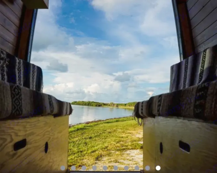 Enjoy the serene waterfront from your RV rental. Inside a van overlooking a bay with green shores.. Mercedes Sprinter 2013