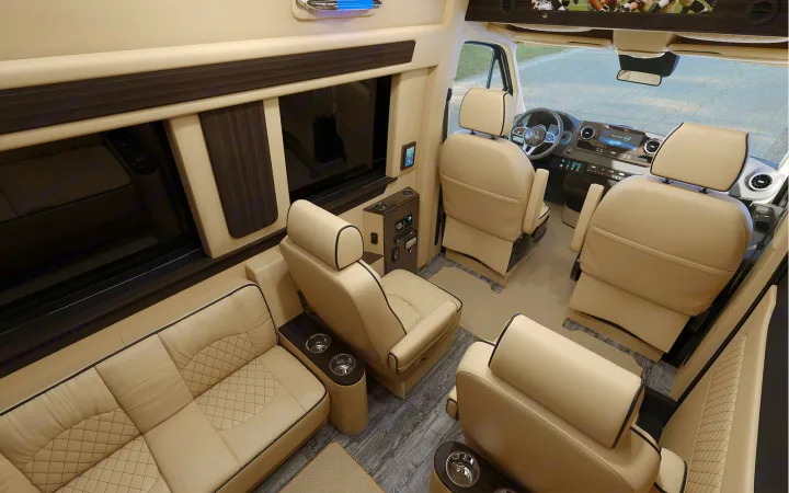 Upscale RV rental interior with cream leather seating, dark wood accents, and TV, showing the front cockpit area.. Ultimate Toys Ultimate Cruiser 2022