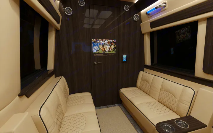 Plush rv rental interior: facing cream benches, TV, and modern wood paneling offer a luxurious, comfortable travel space.. Ultimate Toys Ultimate Cruiser 2022