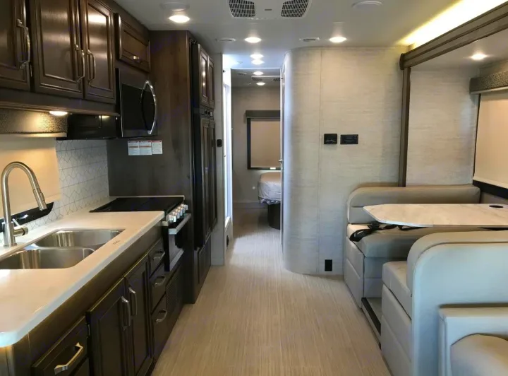 Spacious RV rental interior showing a modern kitchen, dinette area, and hallway to the bedroom.. Entegra Esteem 29v 2022