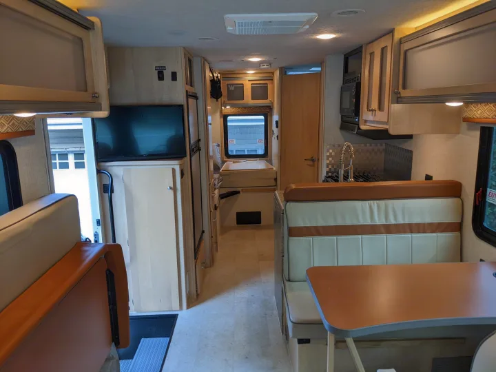 Inside an rv rental: a modern interior with kitchen, dinette, and rear sleeping area, ready for adventure.. Winnebago Brave 2015