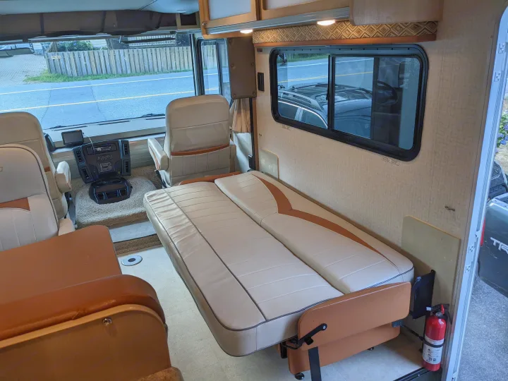 Explore this comfortable RV rental interior, showcasing a convertible sofa bed, front cockpit, and ample living space.. Winnebago Brave 2015