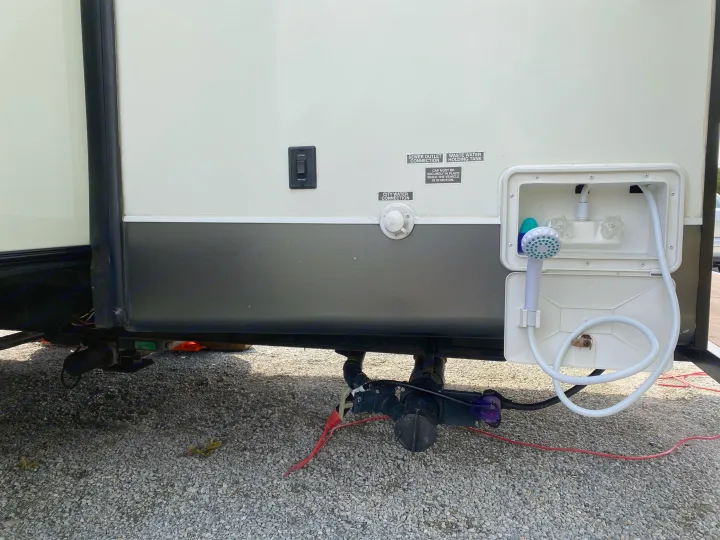 Detailed view of an RV rental's external water & sewer hookups, and outdoor shower unit, essential for camping.. Forest River Salem 2015