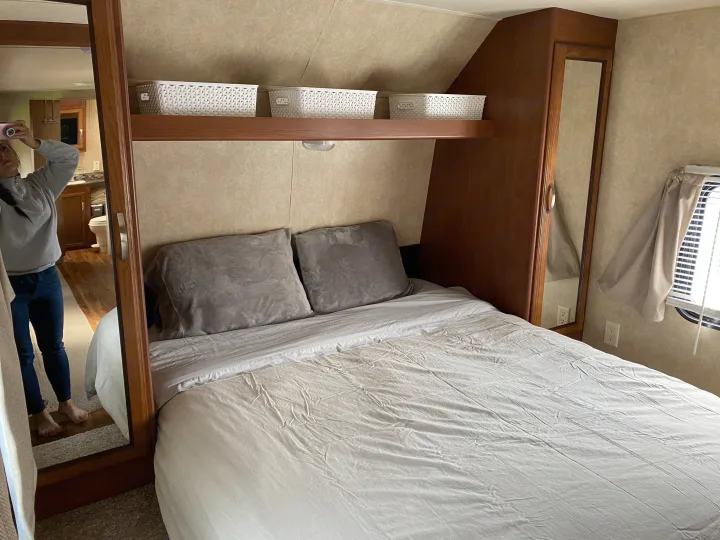 RV rental bedroom: cozy bed, overhead storage, mirrored closet reflecting a person in a compact space.. Forest River Salem 2015