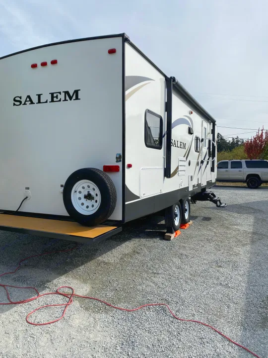 Experience the outdoors! This white Salem travel trailer is set up on a gravel lot, ready for your RV rental adventure.. Forest River Salem 2015