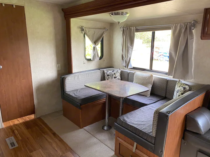 Inside this RV rental, a welcoming dinette features patterned booth seating around a fixed table, with windows offering natural light.. Forest River Salem 2015