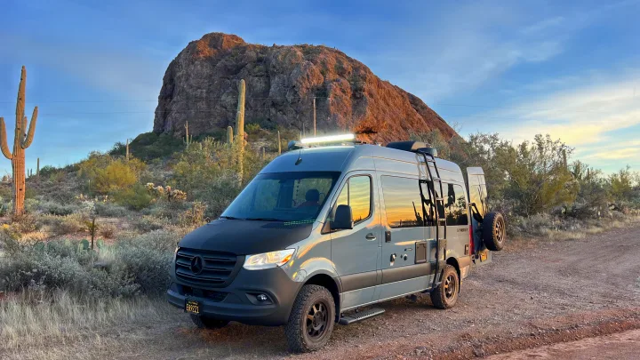 Grey Mercedes-Benz Sprinter RV rental parked in a desert landscape with saguaro cacti and a rocky mountain.. Synergy Mercedes-Benz Sprinter 2022