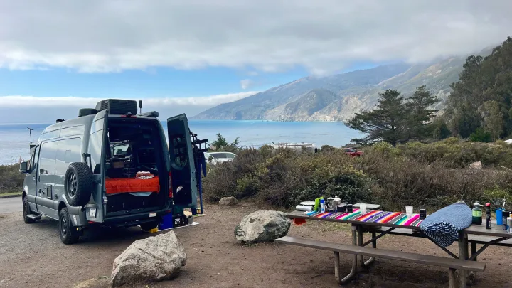 Stunning coastal campsite view featuring an RV rental and a picnic setup by the ocean & mountains.. Synergy Mercedes-Benz Sprinter 2022