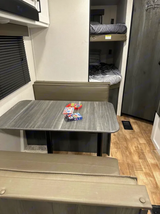 Experience comfort in this RV rental's modern interior, showcasing a practical dining area and upper bunk beds.. Keystone RV Hideout 2022