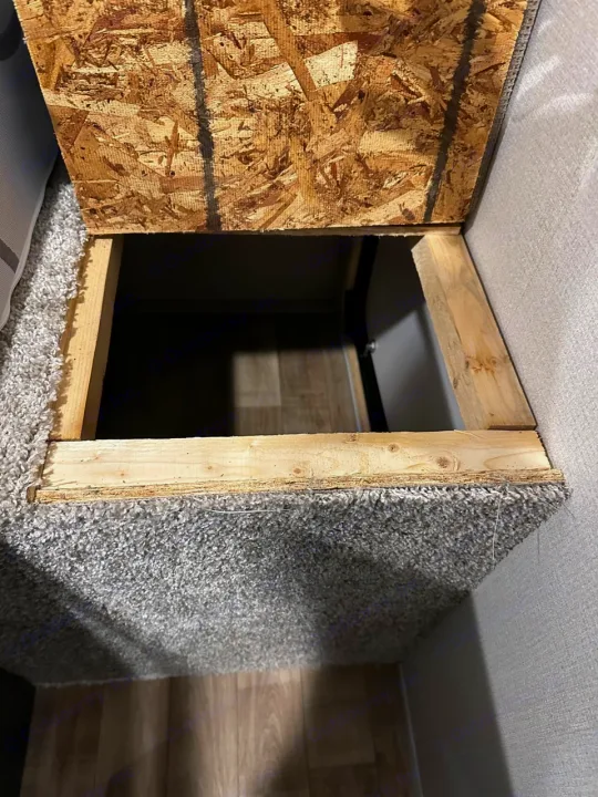 RV rental storage space: an open compartment with wood framing, an OSB panel, and grey carpeted walls.. Keystone RV Hideout 2022