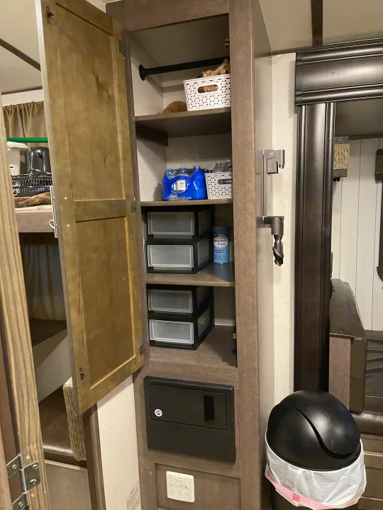 RV rental interior: an open cabinet with organized shelves, including water and storage bins. Smart, compact living space.. Crossroads RV Sunset Trail Super Lite 2018