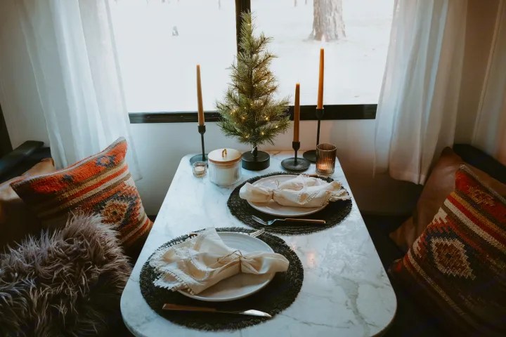 Intimate RV rental dining nook with festive mini tree, glowing candles, and two place settings. Perfect for cozy meals.. Dutchmen Kodiak Cub 2020