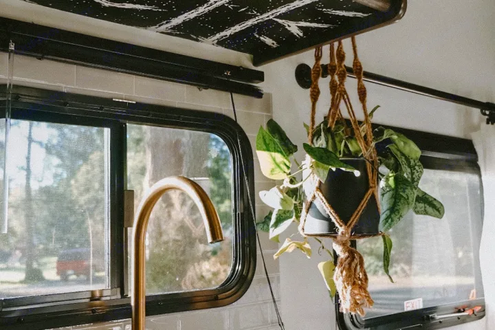 Inside an RV rental: golden faucet, window view, and a charming hanging plant create a cozy home on wheels.. Dutchmen Kodiak Cub 2020