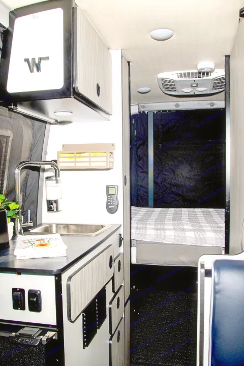 Experience a well-equipped RV rental interior featuring a functional kitchenette, comfy bed, and climate control.. Winnebago Revel 2023