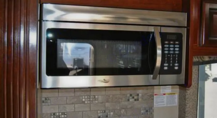 A sleek stainless steel microwave is built into the modern kitchen cabinetry of this RV rental, over a tiled backsplash.. Jamboree Jamboree Motorhome 2017