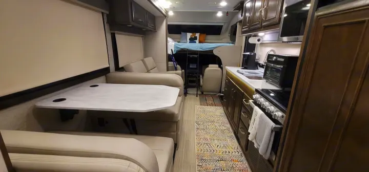 RV rental interior: A full kitchen, dinette area, and an accessible overhead bed are visible, showcasing functional space.. Entegra Esteem 29v 2022
