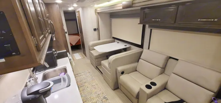 Spacious RV rental interior featuring a modern kitchen, dining booth, and comfortable recliner seats. Bedroom visible.. Entegra Esteem 29v 2022