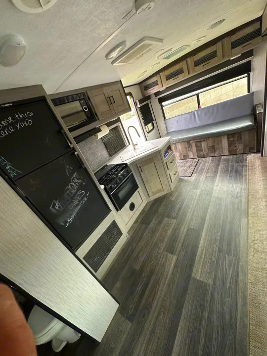 Bright and clean RV rental interior showing kitchen appliances, booth seating, and overhead cabinets.. Heartland Other 2021