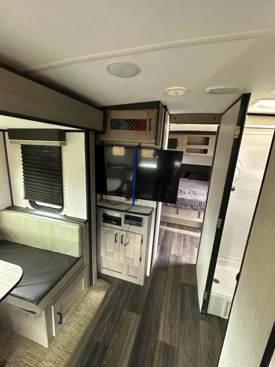 Modern RV rental interior with dinette, TV, and views into bedroom & bathroom. Ideal for your next road trip adventure.. Heartland Other 2021
