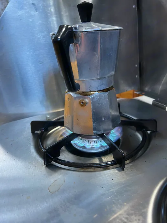 Fresh coffee brewing in an RV rental kitchen: a moka pot on a compact gas stove, ready to fuel adventure.. Little Guy Silver Shadow 2016