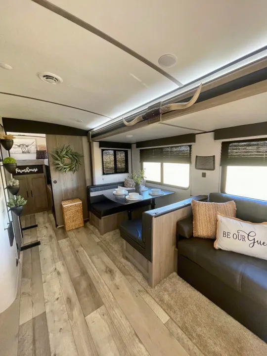 Modern farmhouse RV rental interior: cozy dining booth, sofa, wood floors & rustic decor for your travels.. Keystone RV Springdale 2021