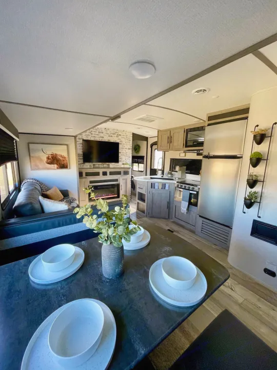 Spacious RV rental interior: modern kitchen, dining area, and living room with a fireplace.. Keystone RV Springdale 2021