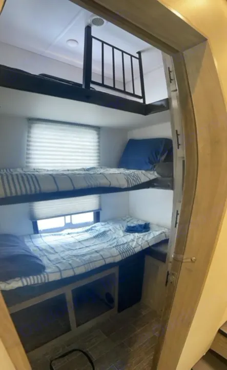 RV rental bunk beds with privacy curtains and a ladder to an upper sleeping loft. Cozy camper interior.. Forest River Cherokee Arctic Wolf 2022