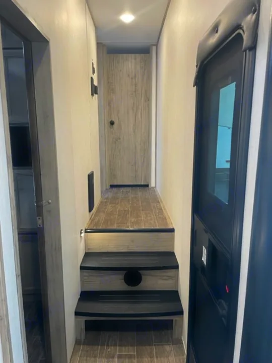 Bright, modern RV rental interior with a skylight and steps leading to an upper area. Perfect for your next adventure!. Forest River Cherokee Arctic Wolf 2022
