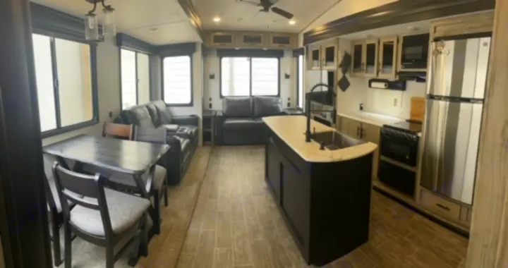 Spacious RV rental interior featuring a modern kitchen, living, and dining area with ample natural light.. Forest River Cherokee Arctic Wolf 2022