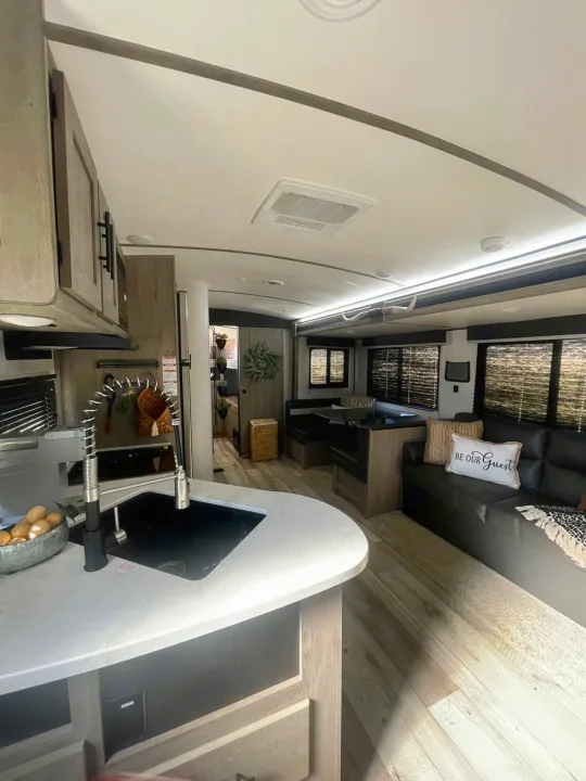 This RV rental's modern interior features a kitchen island, cozy living area, and dinette.. Keystone RV Springdale 2021