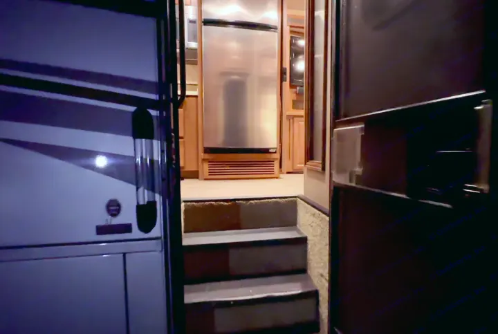 Inside a modern RV rental: view of the kitchen, stainless steel refrigerator, and entrance steps.. Thor Challenger 2015