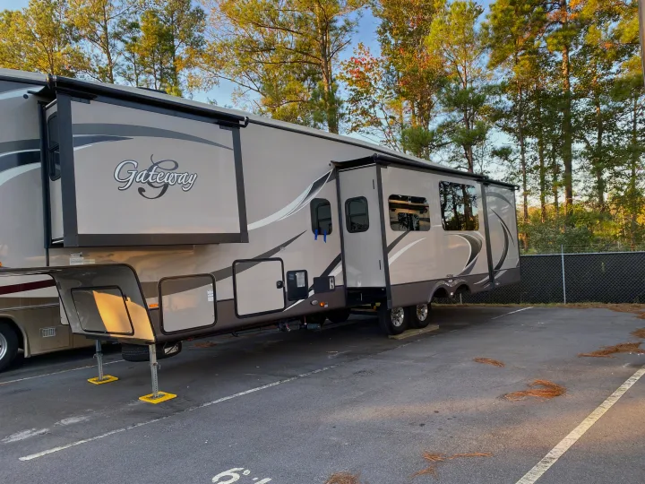This large Gateway fifth-wheel RV, great for rv rental, is parked with slide-outs extended amongst pine trees.. Heartland RVs Gateway 2015