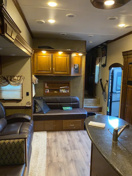 Spacious rv rental interior featuring a cozy living area with a leather sofa, kitchen island, and steps leading up.. Heartland RVs Gateway 2015