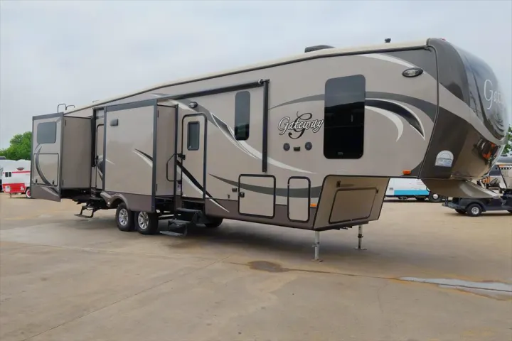 A spacious beige and brown Gateway fifth-wheel RV, with slide-outs extended, showcasing its luxurious design. Ideal for an RV rental.. Heartland RVs Gateway 2015