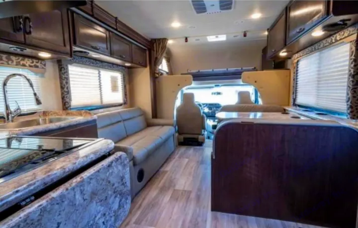 Spacious RV rental interior. Features a modern kitchen, comfortable sofa, and dining booth. Perfect for road trips.. Thor Four Winds 2019