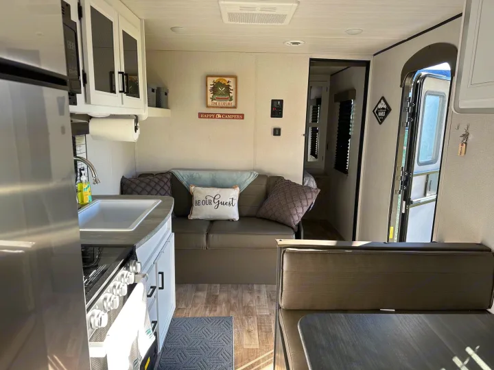 Explore this RV rental's cozy interior, featuring a compact kitchen, comfortable sofa, & dining area.. Keystone RV Hideout 2022