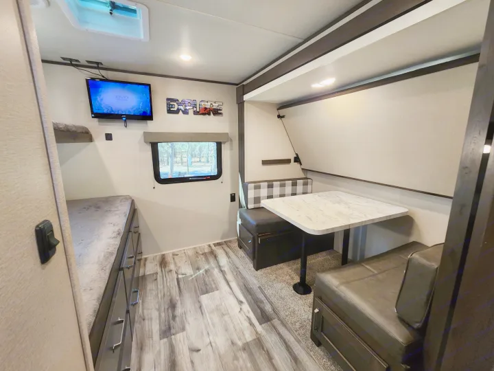 RV rental interior: cozy dinette, TV, bunks, and "Explore" sign. Perfect for adventures with modern amenities.. Grand Design Transend Xplor 315BH 2023