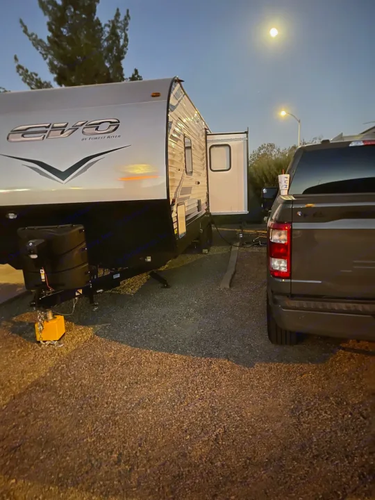 An RV rental, an "EVO by Forest River" travel trailer, with a pickup truck parked under a bright moon at night.. Forest River Evo 2022
