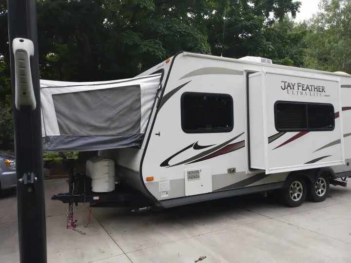 White Jayco Jay Feather hybrid travel trailer parked on concrete, ideal for rv rental adventures.. Jayco Jay Feather Ultra Lite 2013