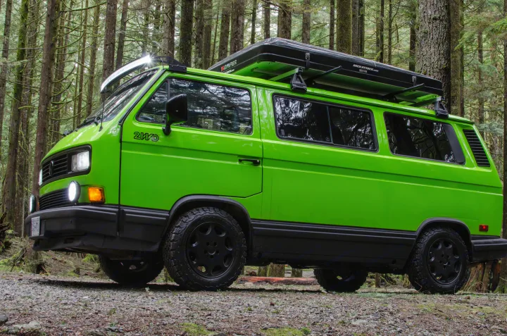 Bright green VW camper van with rooftop tent in a forest setting, ideal for an RV rental adventure.. Volkswagen Vanagon 1989
