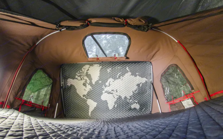 Inside an RV rental, showing a cozy tent interior with a quilted mattress, world map wall, and scenic windows, ready for adventure.. Volkswagen Vanagon 1989