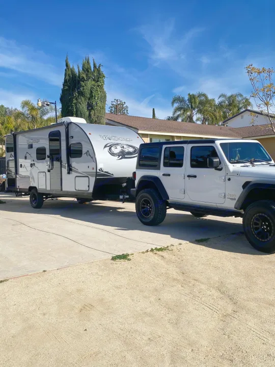White Jeep towing a grey travel trailer, ready for your next rv rental adventure!. Forest River Cherokee Wolf Pup 2022