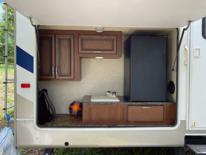 RV rental outdoor kitchen setup: sink, mini-fridge, cabinets for easy outdoor cooking and storage.. Crossroads RV Zinger 2013