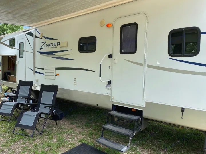 White Zinger RV rental with an extended awning, steps, and lounge chairs for outdoor relaxation.. Crossroads RV Zinger 2013