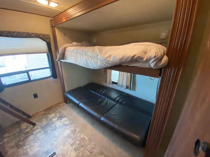 Cozy bunkhouse interior of an RV rental, featuring an upper bed & a convertible futon. Perfect for family trips.. Crossroads RV Zinger 2013