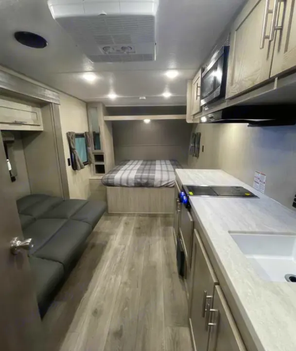 Inside this modern RV rental: a cozy bed, full kitchen, and comfortable seating. Ideal for road trips!. Coachmen Catalina 2022